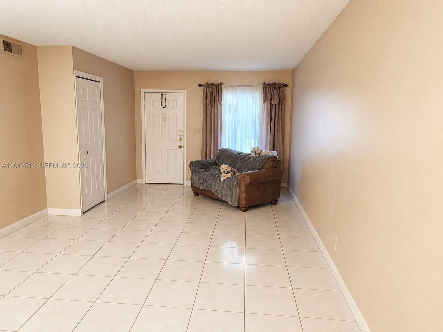 A living room features beige walls, light-colored tile flooring, a brown sofa, and a window — 15619 SW 73rd Cir Ter # 9, Miami FL 33193, MIAMI, FL