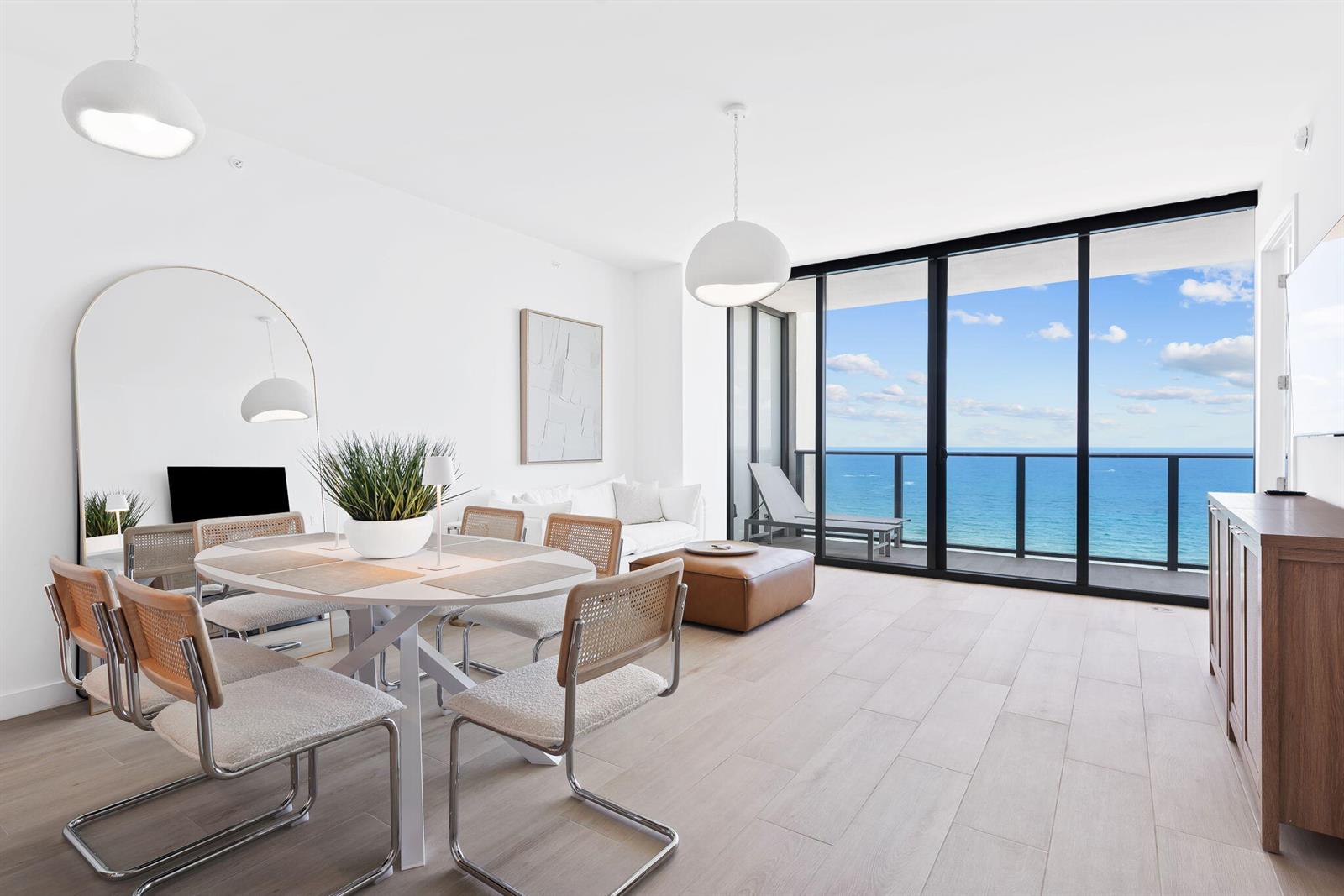 A bright dining and living area features a round table, modern chairs, and floor-to-ceiling windows — 900 N Ocean Boulevard # 1404, Pompano Beach FL 33062, POMPANO BEACH, FL