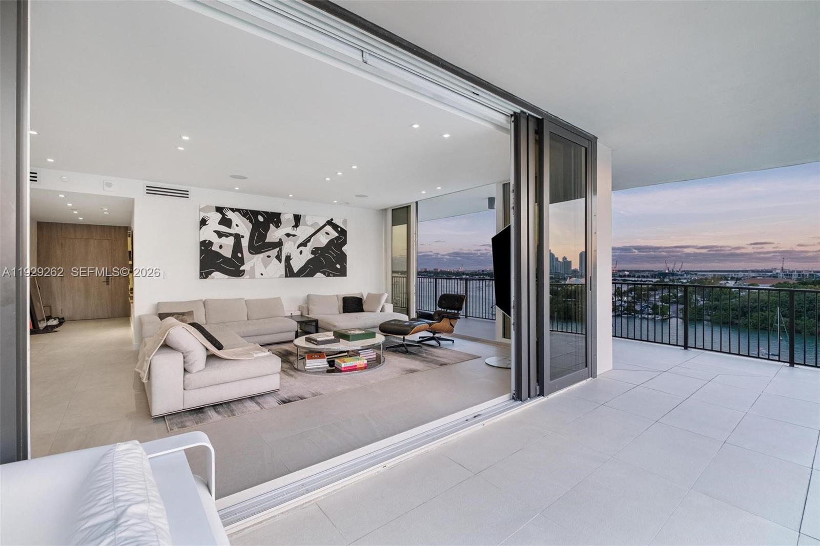 A modern living room opens onto a spacious balcony with panoramic waterfront and city views — 1000 Venetian Way # 1004, Miami FL 33139, MIAMI, FL