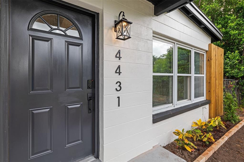 A dark grey front door sits next to a white wall with vertical house numbers — 4431 SOUTHMORE DRIVE, ORLANDO, FL