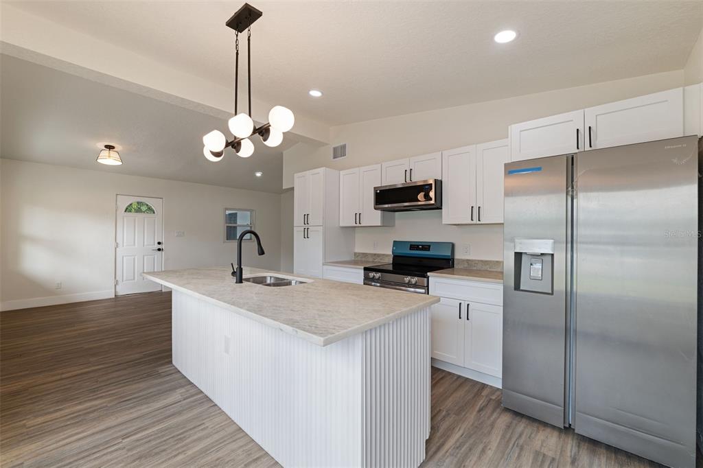 A modern kitchen features white cabinets, stainless steel appliances, a center island, and bar seating — 4431 SOUTHMORE DRIVE, ORLANDO, FL