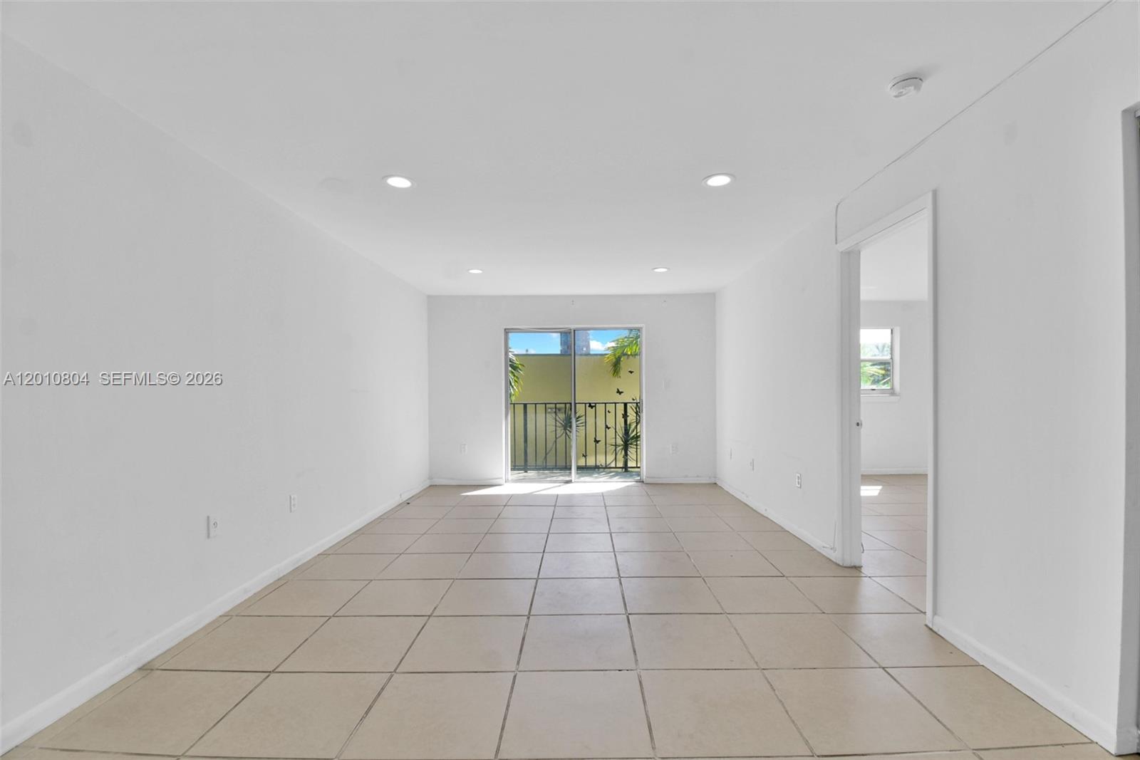 An empty room with white walls, recessed lighting, tile flooring, and a sliding glass door — 618 Euclid Ave # 303, Miami Beach FL 33139, MIAMI BEACH, FL
