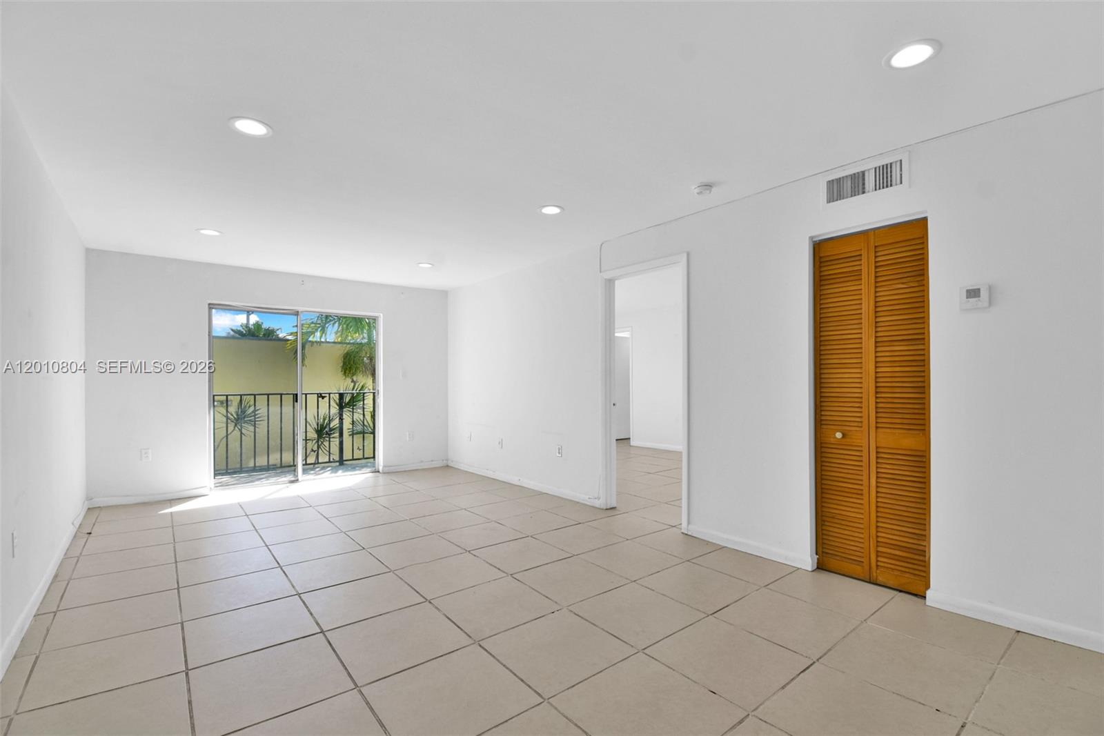 A bright, empty living room features white walls, tile flooring, recessed lighting, and a balcony — 618 Euclid Ave # 303, Miami Beach FL 33139, MIAMI BEACH, FL
