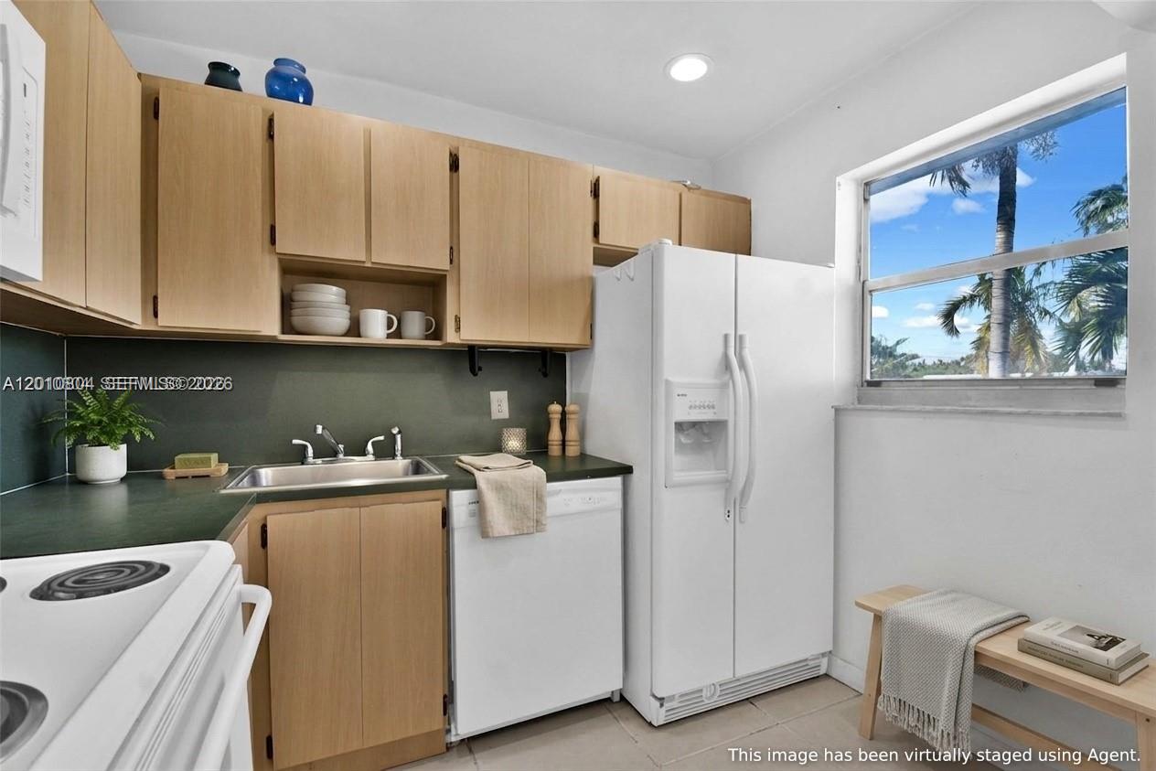A kitchen features light wood cabinets, white appliances, a dark countertop, and a window — 618 Euclid Ave # 303, Miami Beach FL 33139, MIAMI BEACH, FL