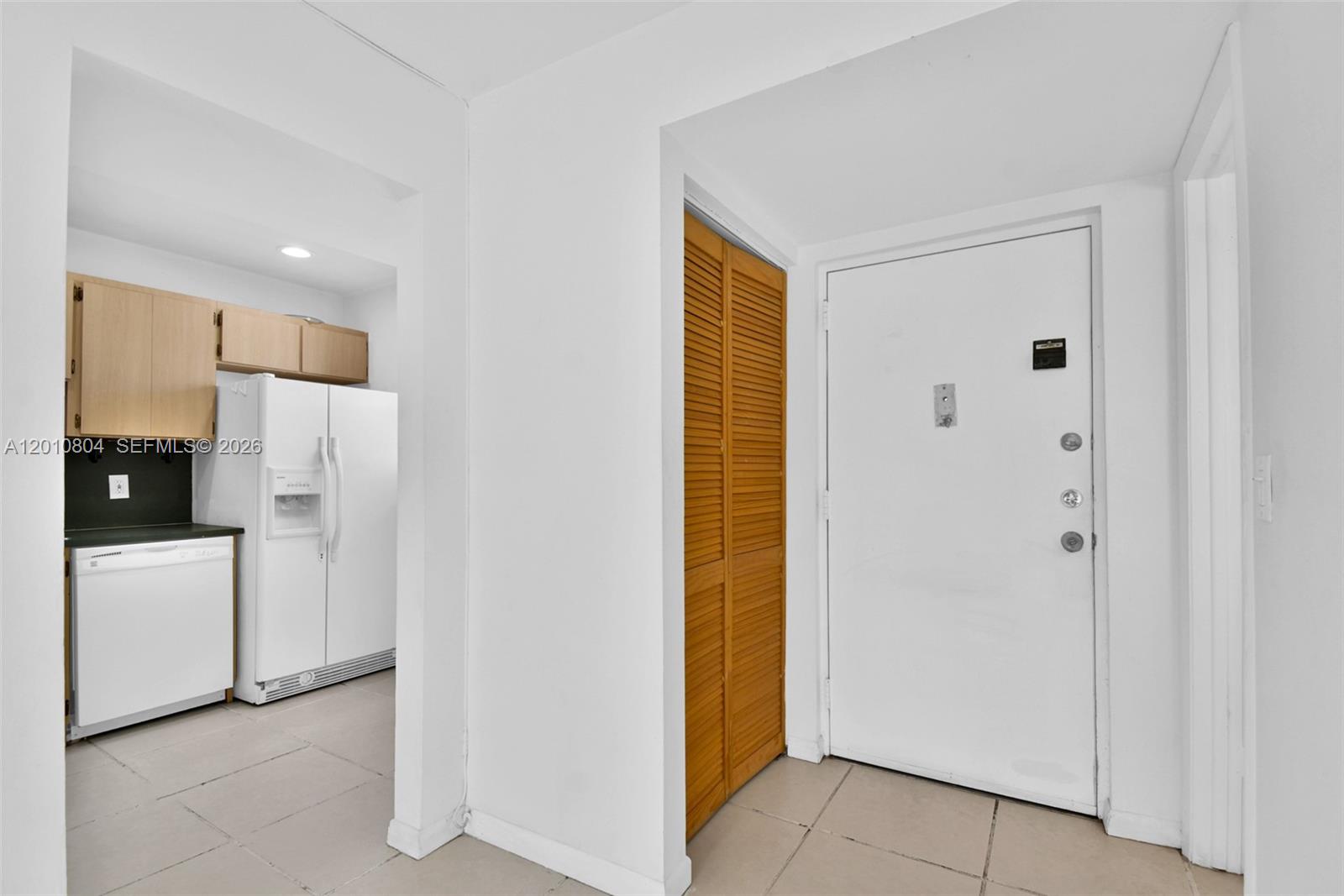 A white front door sits next to a wooden louvered closet door near a kitchen — 618 Euclid Ave # 303, Miami Beach FL 33139, MIAMI BEACH, FL