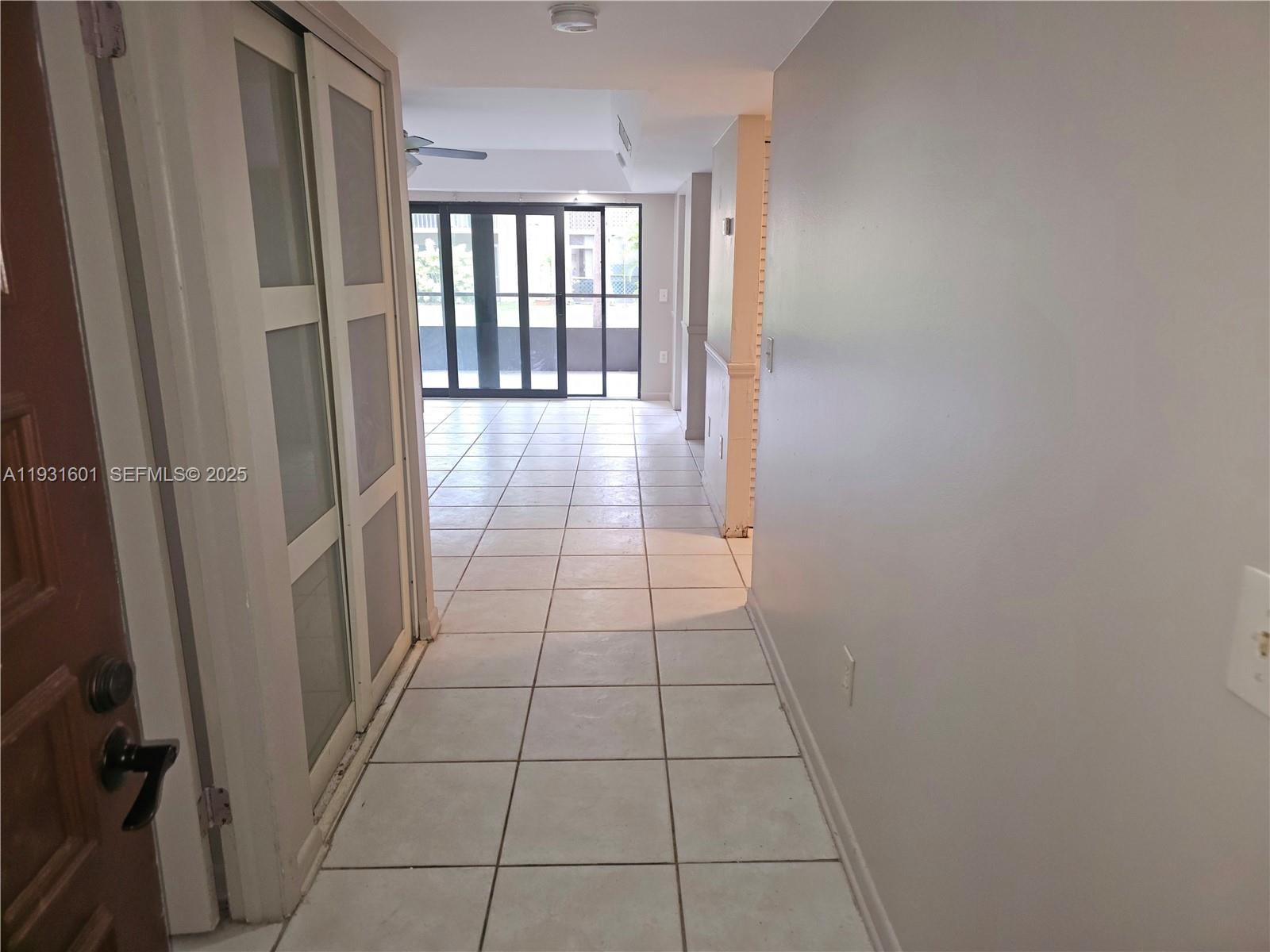 A tiled hallway leads toward a living area with large glass sliding doors — 8415 SW 107th Ave # 116W, Miami FL 33173, MIAMI, FL