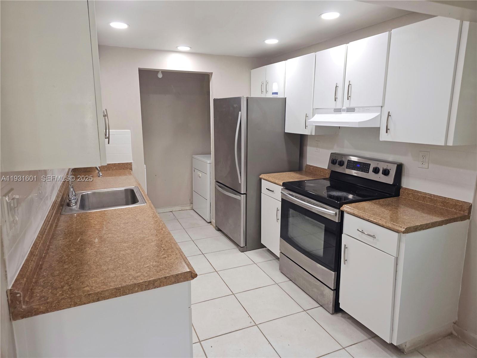 A kitchen features white cabinets, brown countertops, stainless steel appliances, and white tile flooring — 8415 SW 107th Ave # 116W, Miami FL 33173, MIAMI, FL