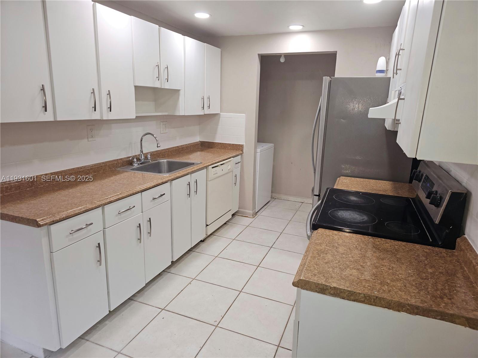 A kitchen features white cabinets, tan laminate countertops, a stainless steel sink, and tile flooring — 8415 SW 107th Ave # 116W, Miami FL 33173, MIAMI, FL