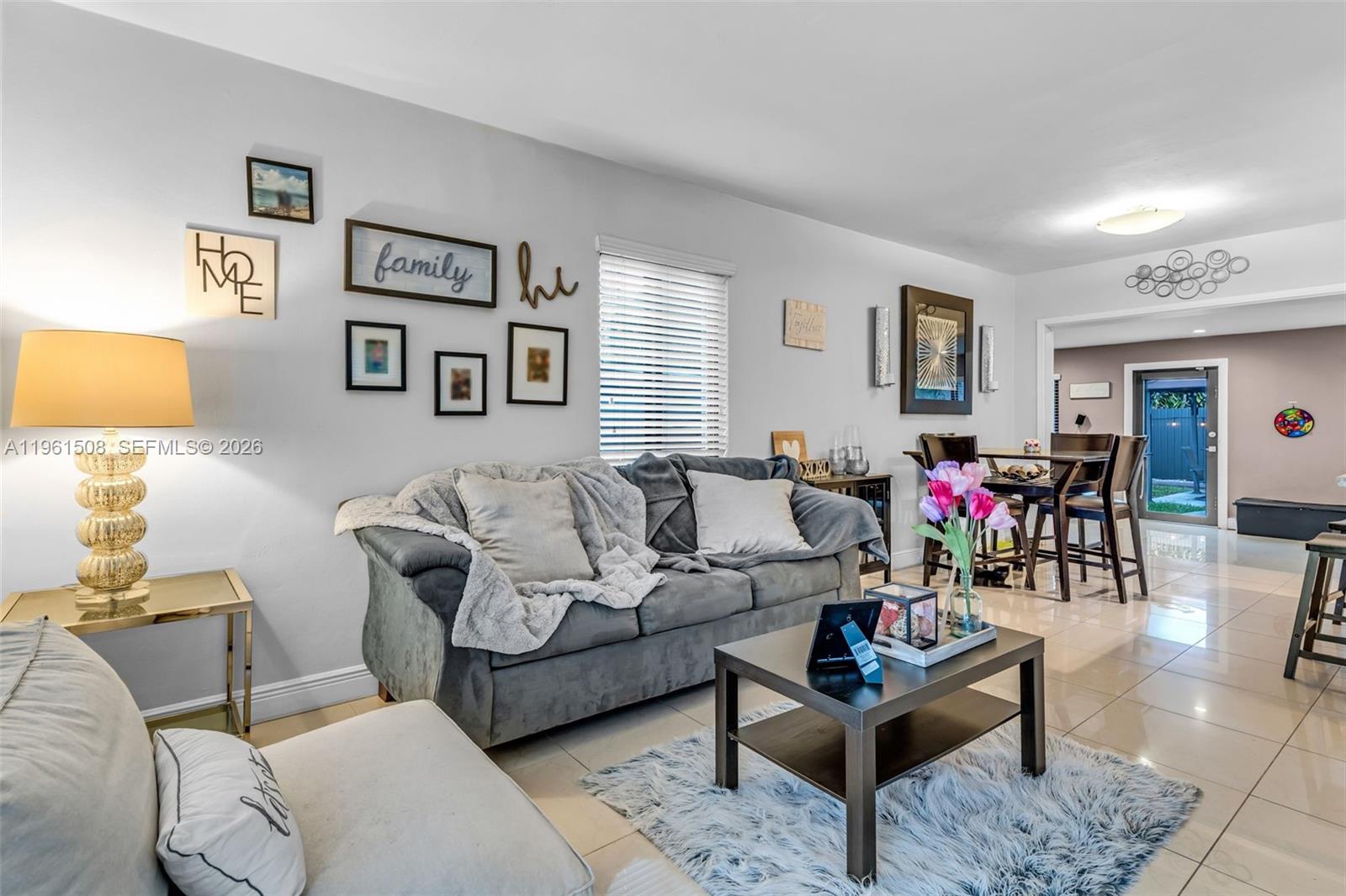 A living room features a grey sofa, a coffee table, and tile flooring — 7585 SW 28th St, Miami FL 33155, MIAMI, FL