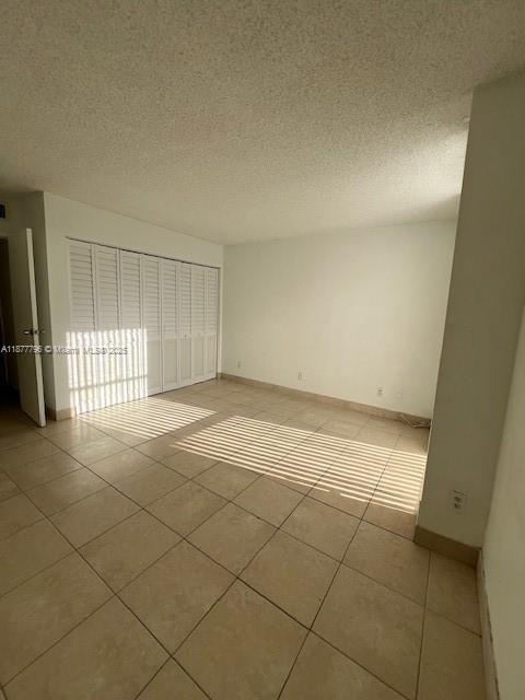 An empty bedroom features light-colored tile flooring, white walls, and a white louvered closet door — 13499 Biscayne Blvd # 602, North Miami FL 33181, NORTH MIAMI, FL