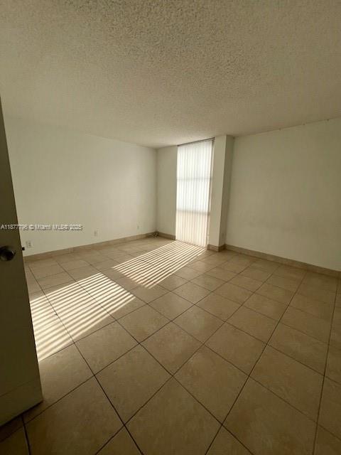 An empty room features beige tile flooring, white walls, and a window with vertical blinds — 13499 Biscayne Blvd # 602, North Miami FL 33181, NORTH MIAMI, FL