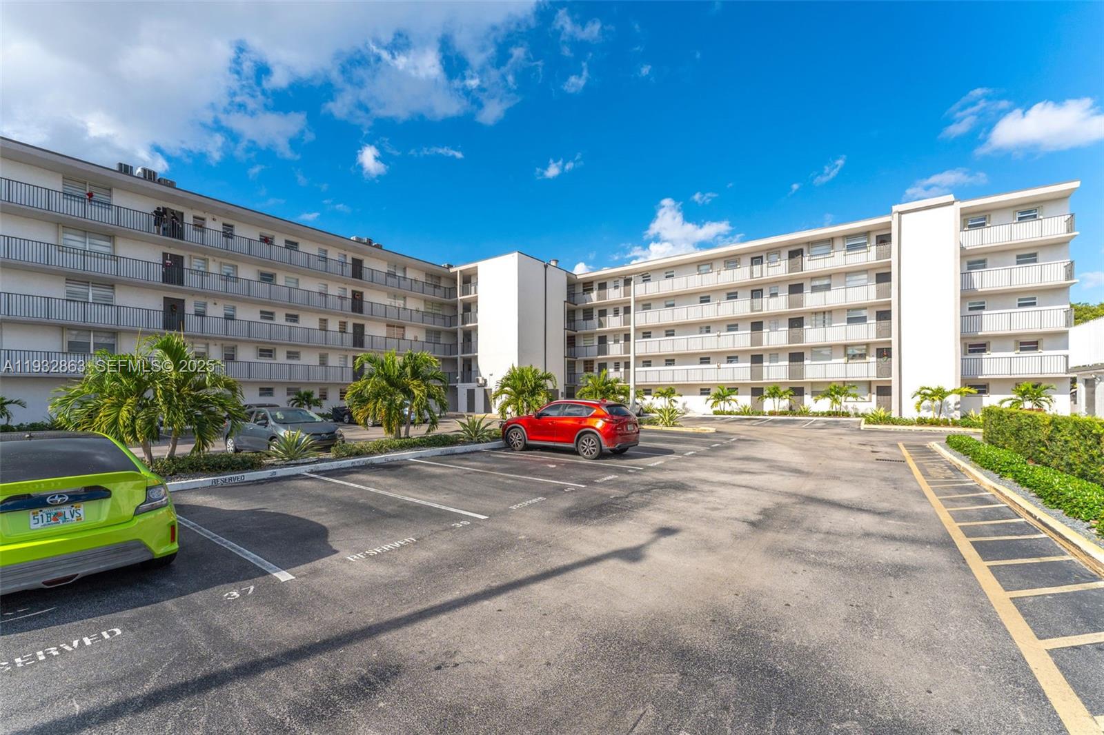 A multi-story apartment building features exterior balconies and a paved parking lot in front — 14180 SW 84th St # G, Miami FL 33183, MIAMI, FL