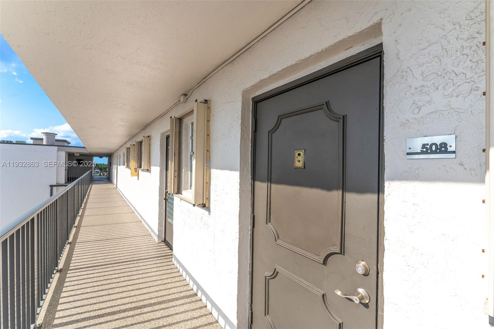 An exterior walkway leads to a brown apartment door labeled 508 in a white building — 14180 SW 84th St # G, Miami FL 33183, MIAMI, FL