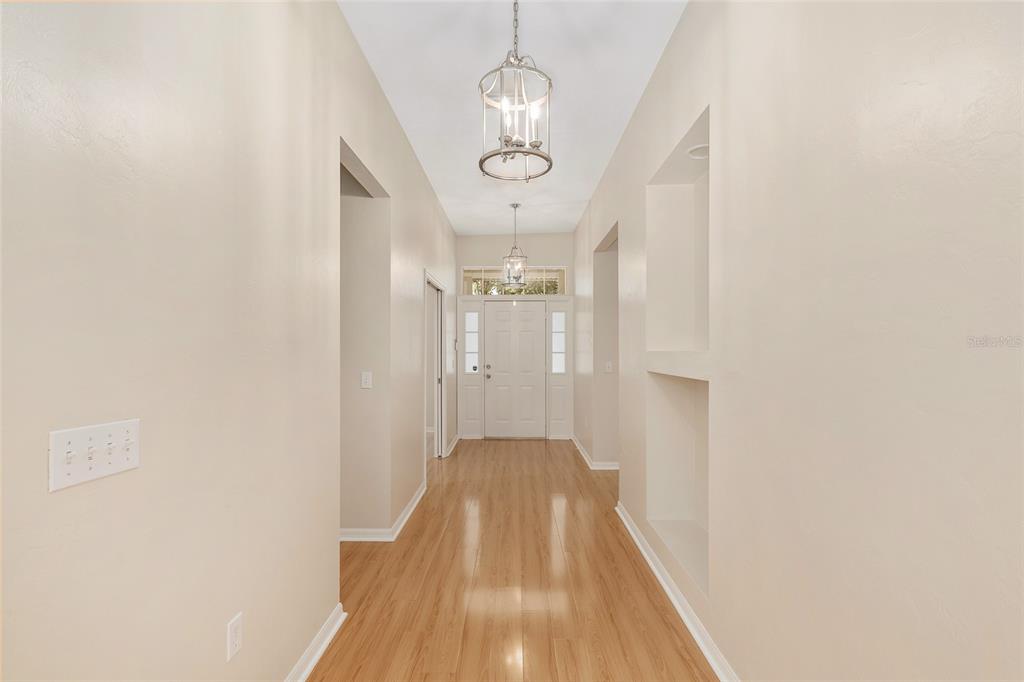 A bright entryway features light wood flooring, two wall niches, and two hanging pendant lights — 8632 SW 76TH PLACE, GAINESVILLE, FL
