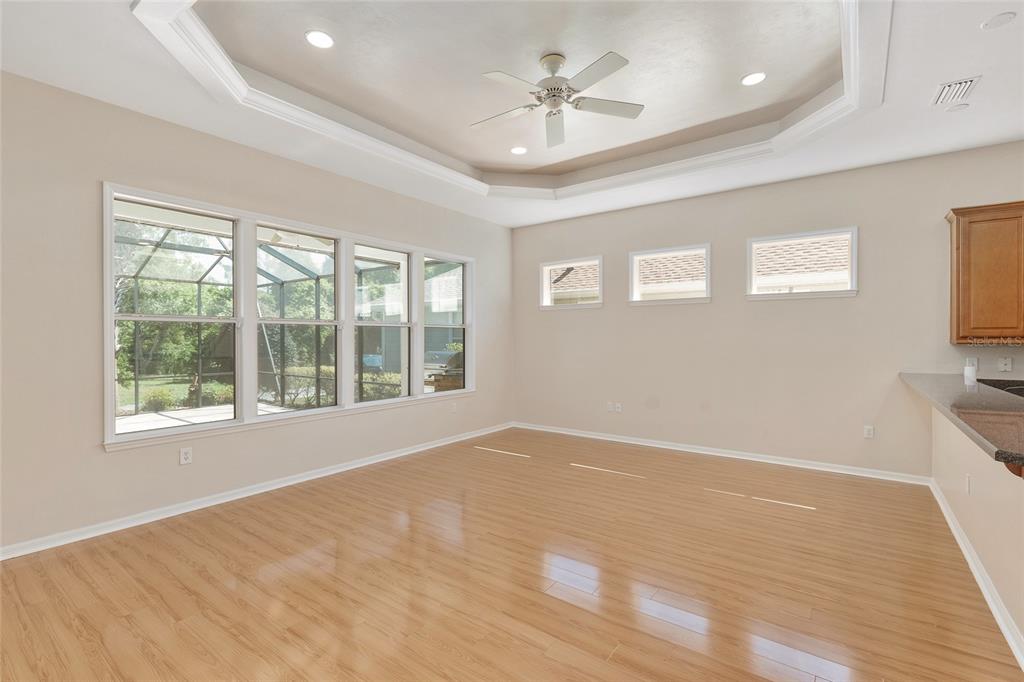 An empty room with light wood flooring, a tray ceiling, and large windows — 8632 SW 76TH PLACE, GAINESVILLE, FL