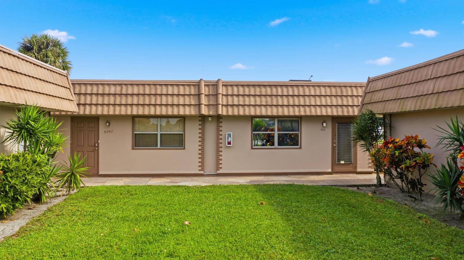 A single-story building exterior with a brown tiled mansard roof, two doors, and a lawn — 341 Seville O, Delray Beach FL 33446, DELRAY BEACH, FL