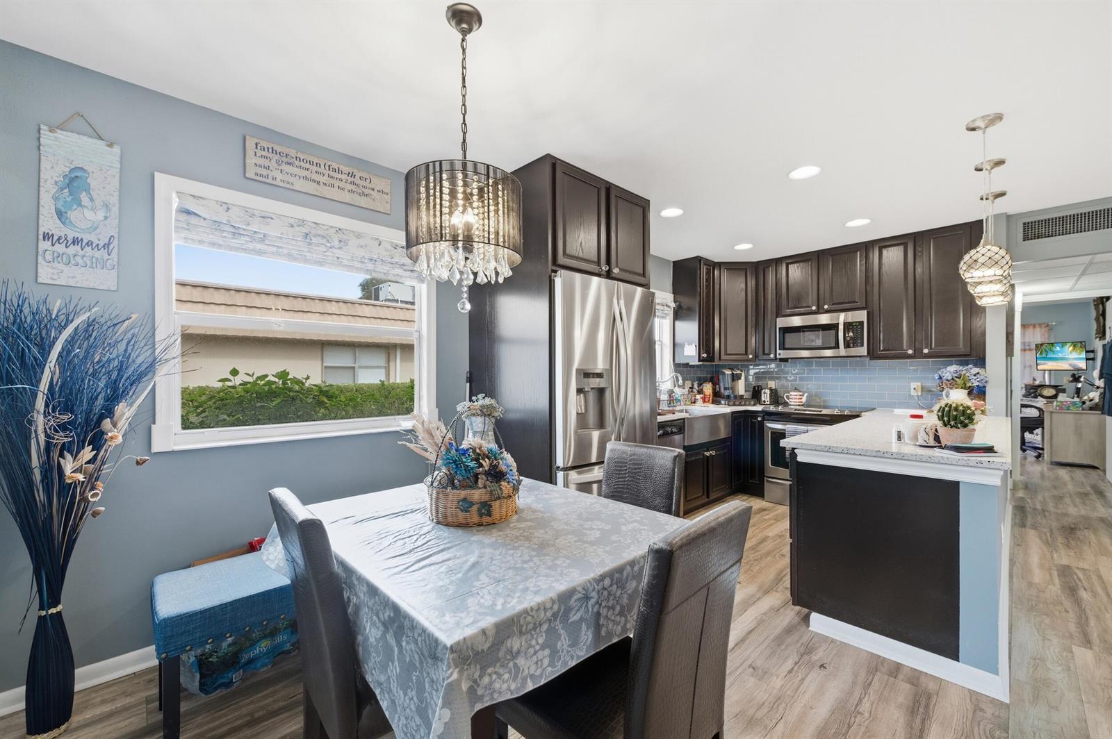 A kitchen and dining area with dark cabinets, stainless steel appliances, and a crystal chandelier — 341 Seville O, Delray Beach FL 33446, DELRAY BEACH, FL