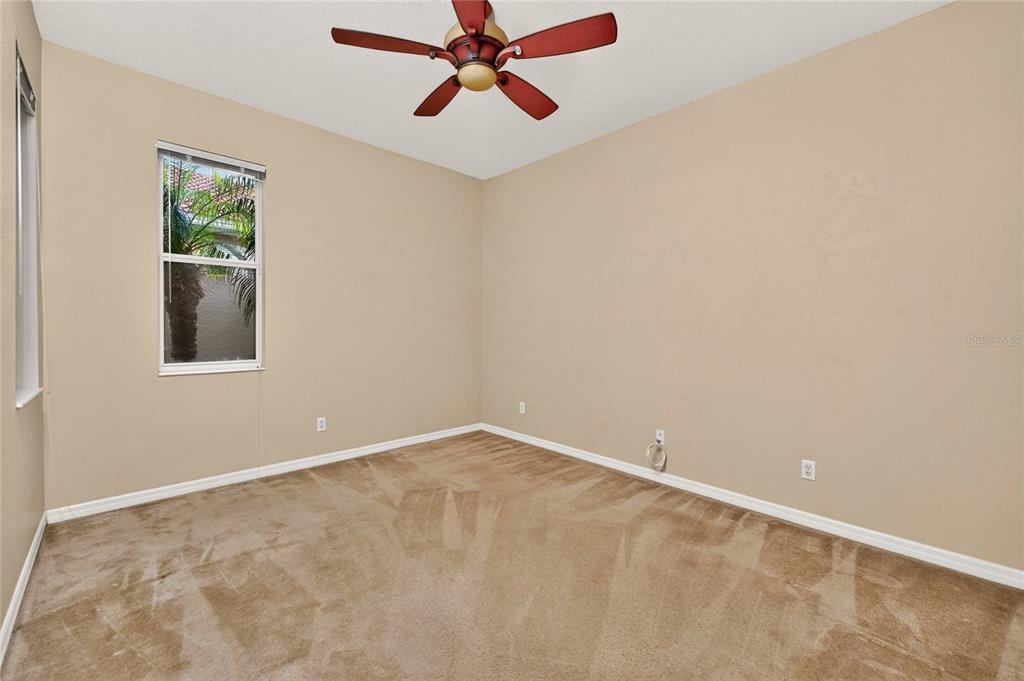 An empty bedroom features beige walls, tan carpeting, a ceiling fan, and a single window — 246 MESTRE PLACE, NORTH VENICE, FL