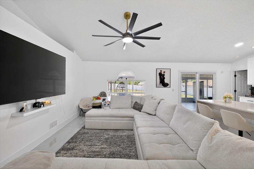 A living room features a large sectional sofa, a wall-mounted television, and a ceiling fan — 4096 LANDOVER BOULEVARD, SPRING HILL, FL