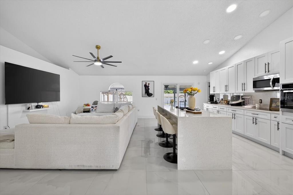 An open-concept living room and kitchen featuring white cabinetry, a large island, and tile flooring — 4096 LANDOVER BOULEVARD, SPRING HILL, FL
