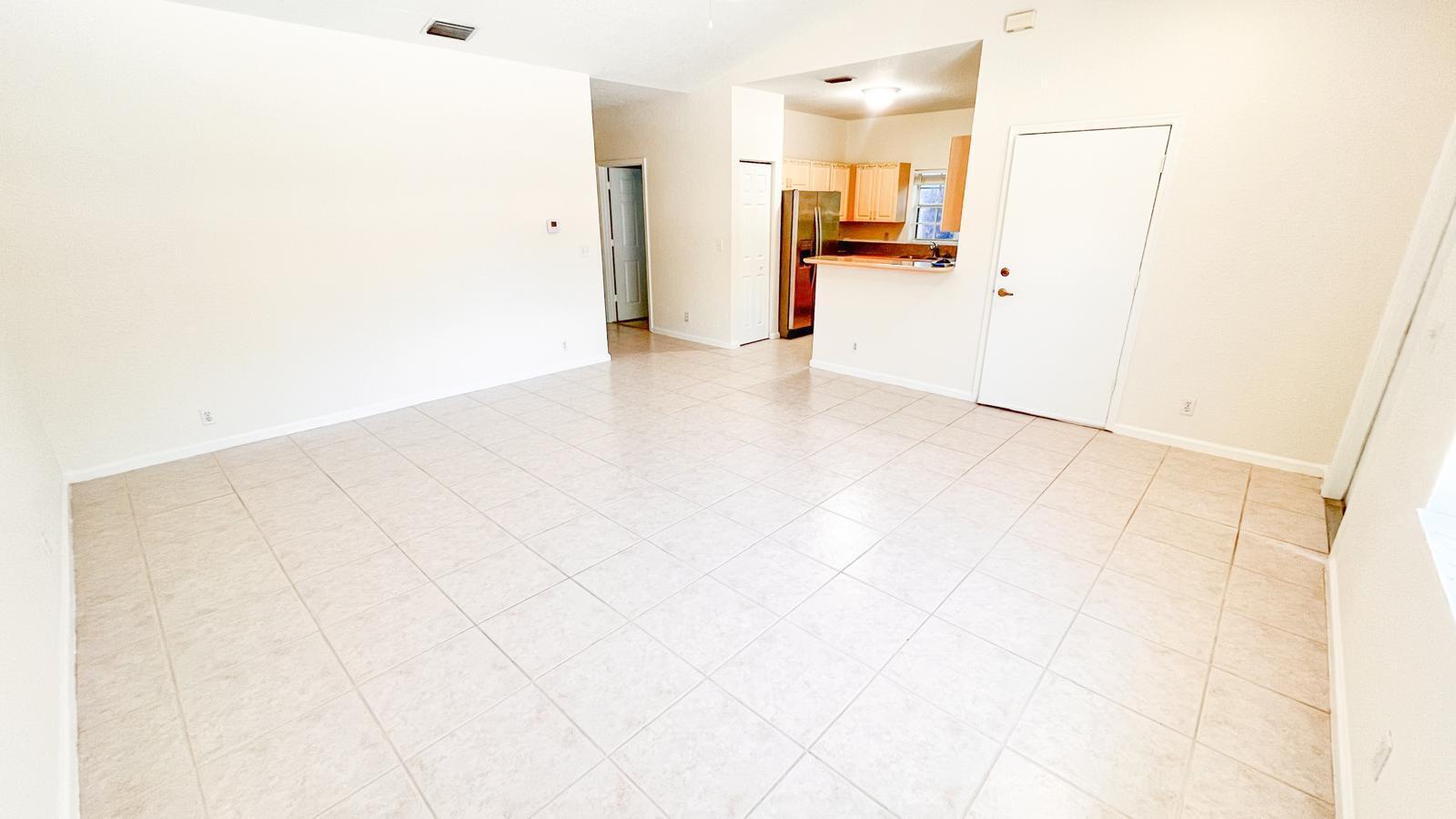 An open-concept living area features light-colored floor tiles and a view into the kitchen — 1440 Hawthorne Place, Wellington FL 33414, WELLINGTON, FL