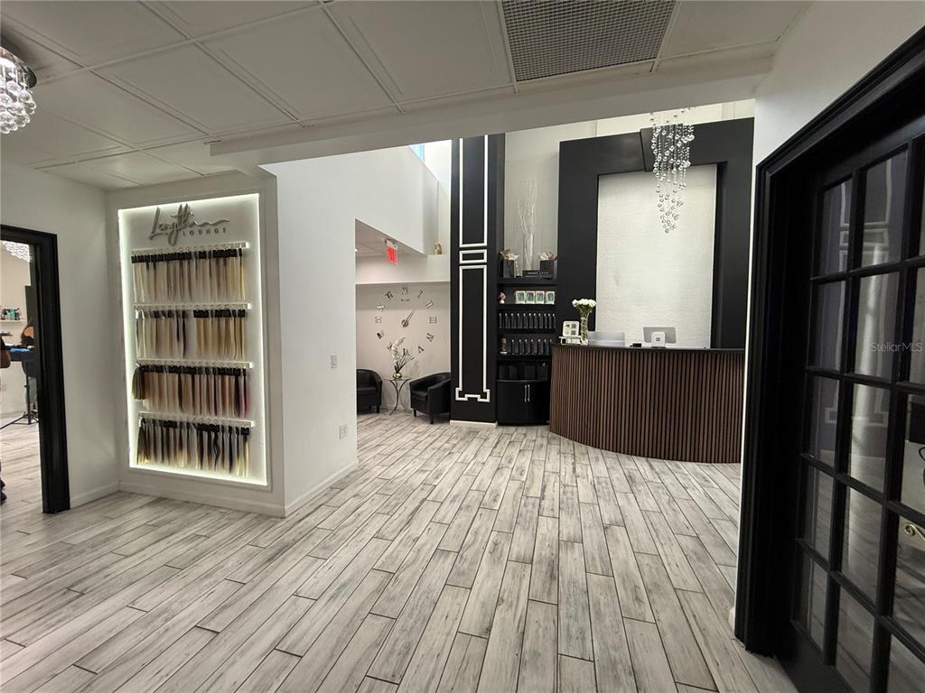 A modern salon reception area features a wood-slatted desk, hair extension display, and wood-look flooring — 1235 N ORANGE AVENUE, ORLANDO, FL