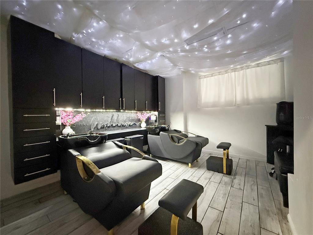 A salon room features two black shampoo chairs, dark cabinetry, and a draped ceiling — 1235 N ORANGE AVENUE, ORLANDO, FL