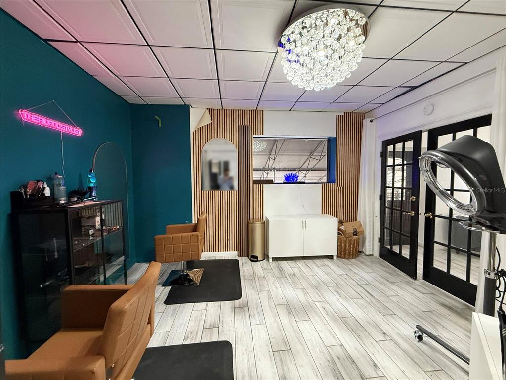 A salon room features two tan chairs, wood-slat wall accents, and a crystal chandelier — 1235 N ORANGE AVENUE, ORLANDO, FL