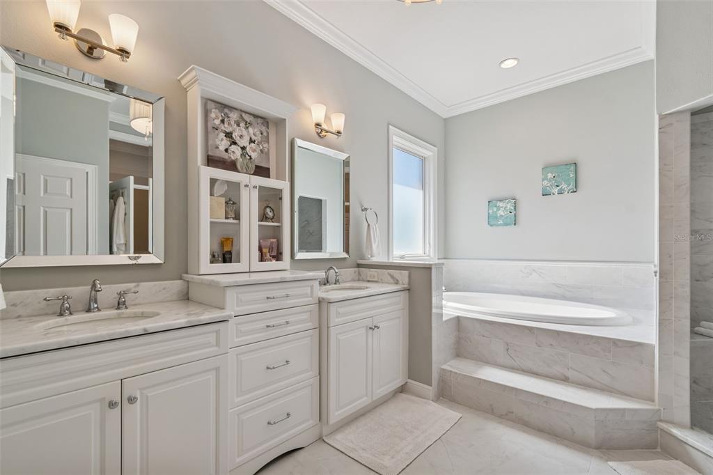 A bathroom features white cabinetry, marble countertops, dual sinks, and a tiled soaking tub — 610 SAXONY BOULEVARD, ST PETERSBURG, FL