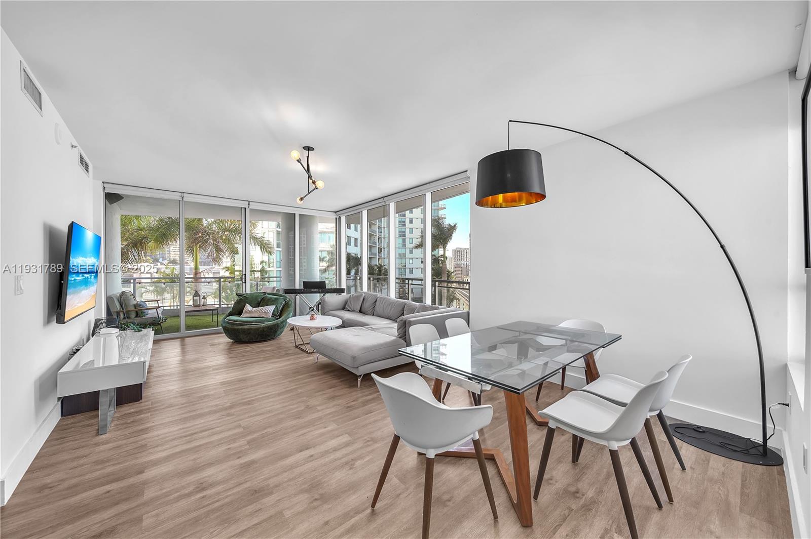 A modern living and dining area features light wood floors, floor-to-ceiling windows, and balcony access — 90 SW 3rd St # 1213, Miami FL 33130, MIAMI, FL