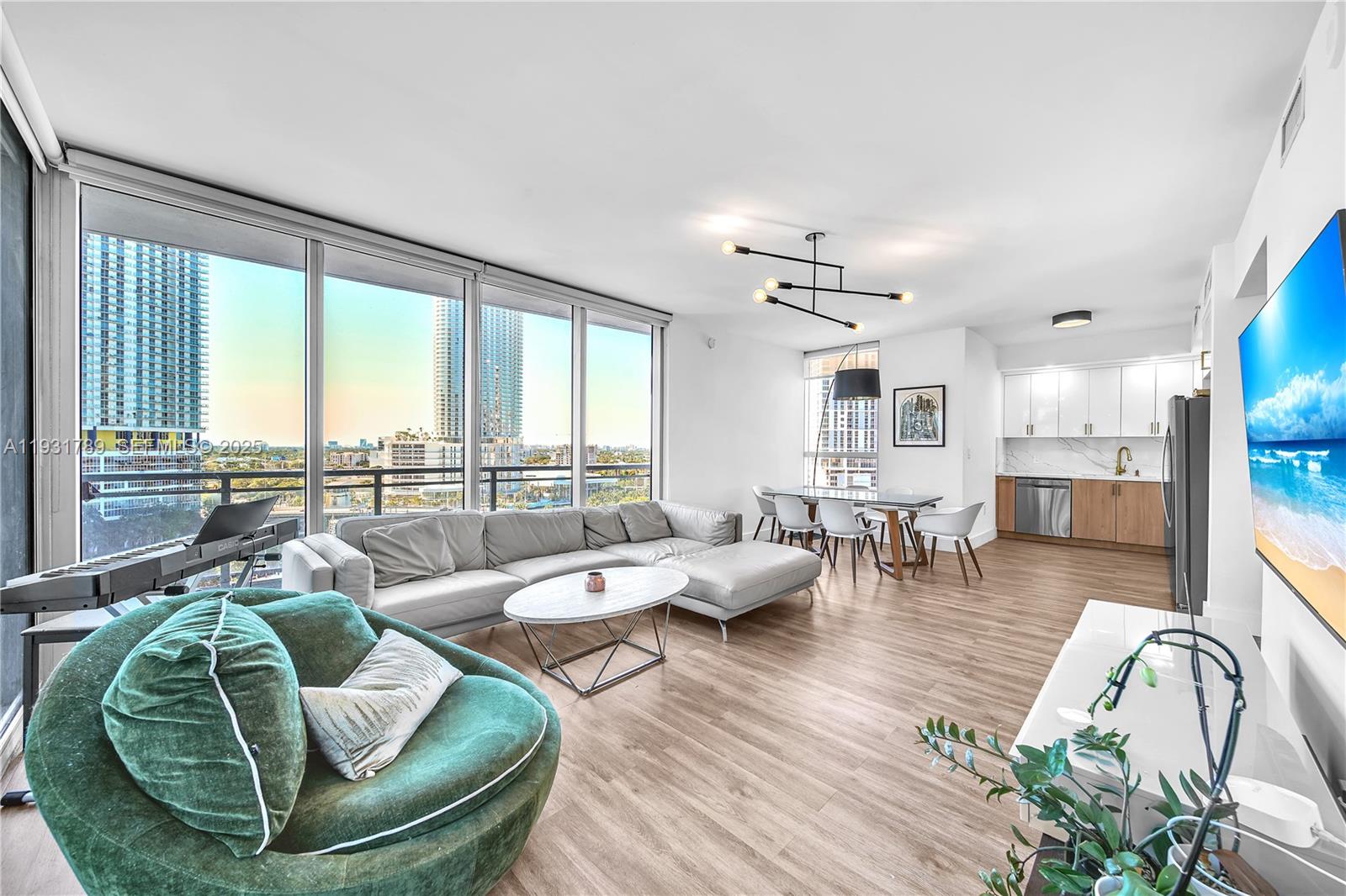 A modern living room and kitchen area with floor-to-ceiling windows overlooking a city skyline — 90 SW 3rd St # 1213, Miami FL 33130, MIAMI, FL