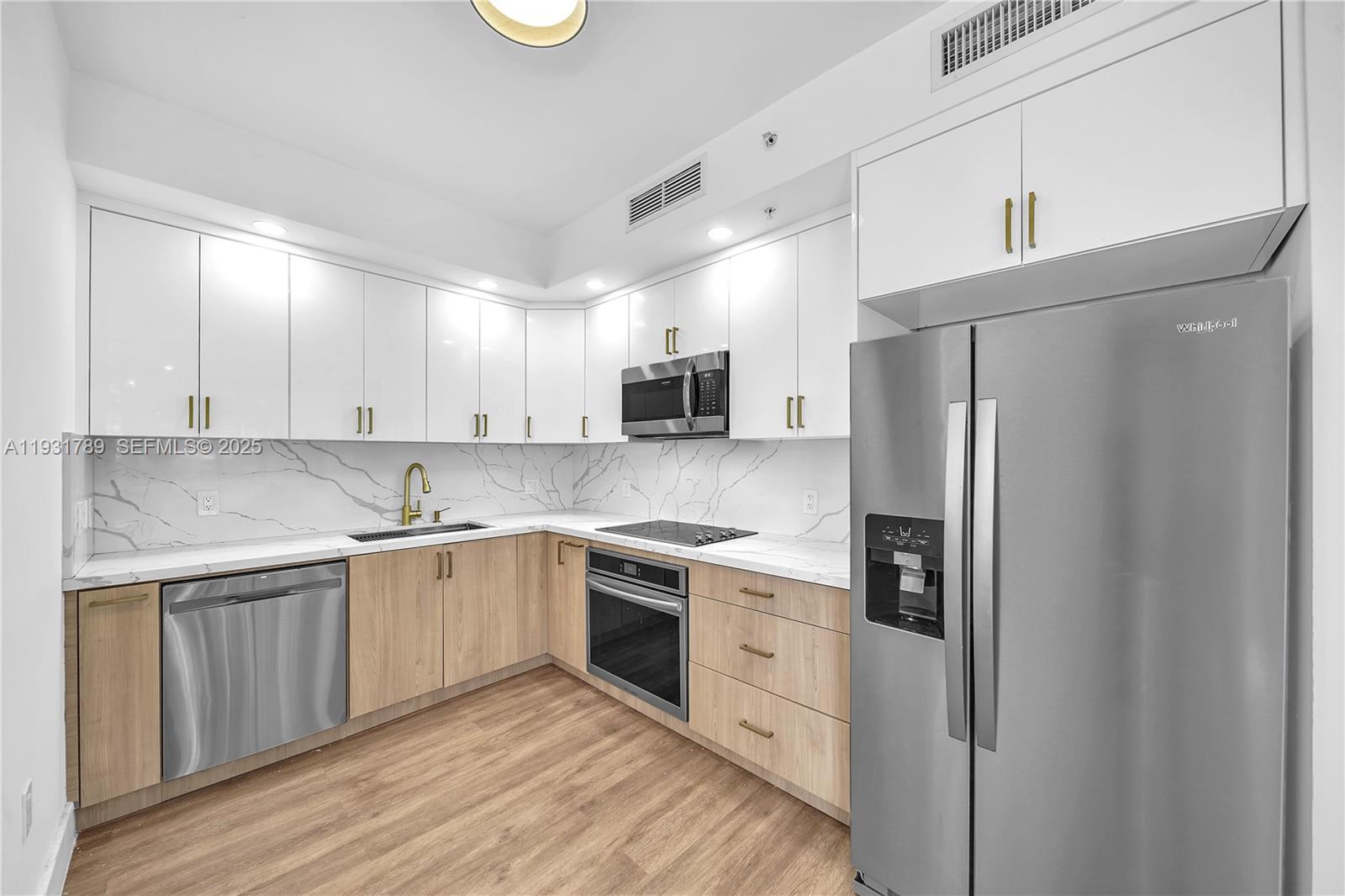 A modern kitchen features white upper cabinets, light wood lower cabinets, and marble-patterned countertops — 90 SW 3rd St # 1213, Miami FL 33130, MIAMI, FL