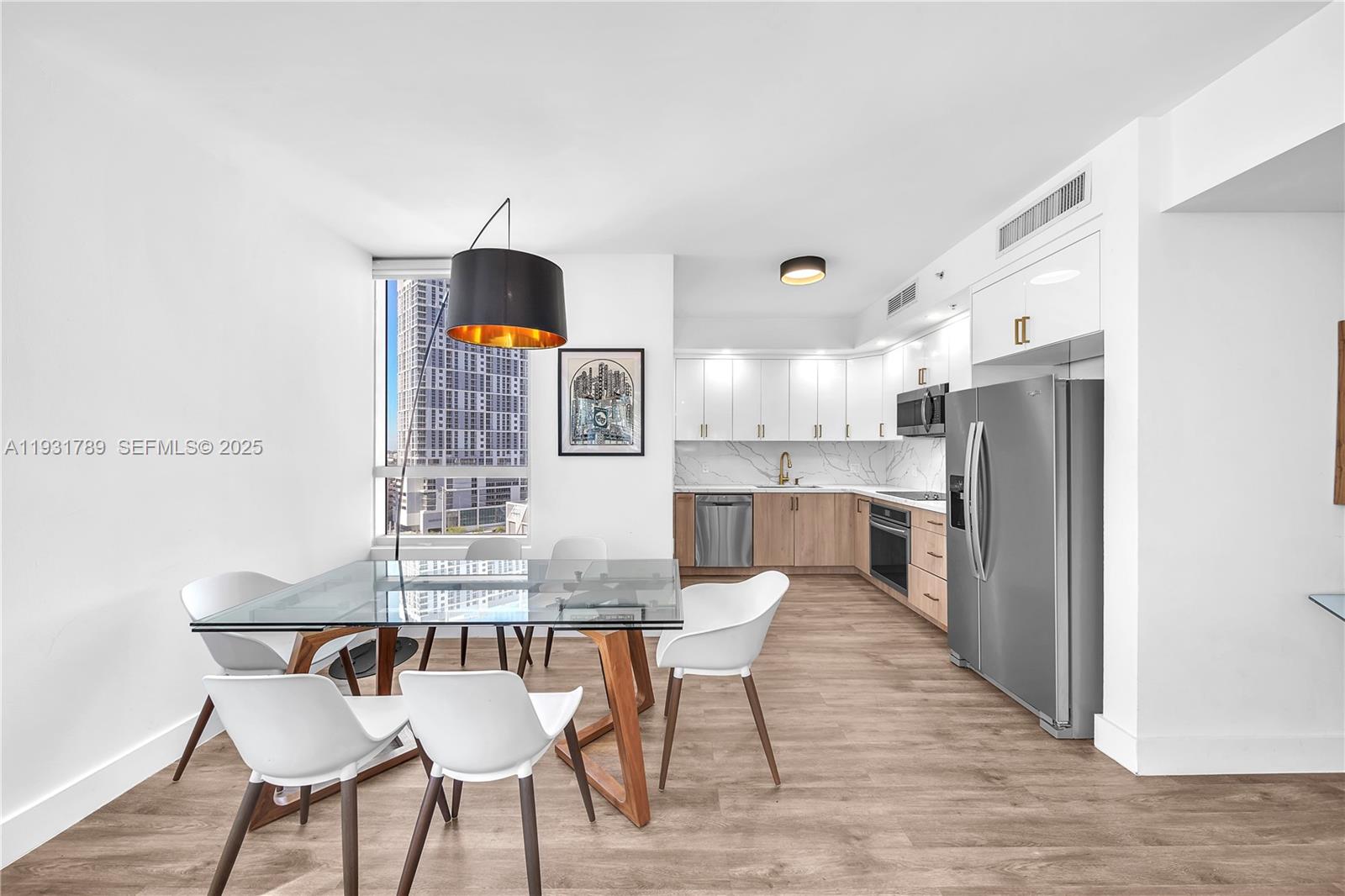 A modern kitchen and dining area features white cabinets, stainless steel appliances, and a window — 90 SW 3rd St # 1213, Miami FL 33130, MIAMI, FL