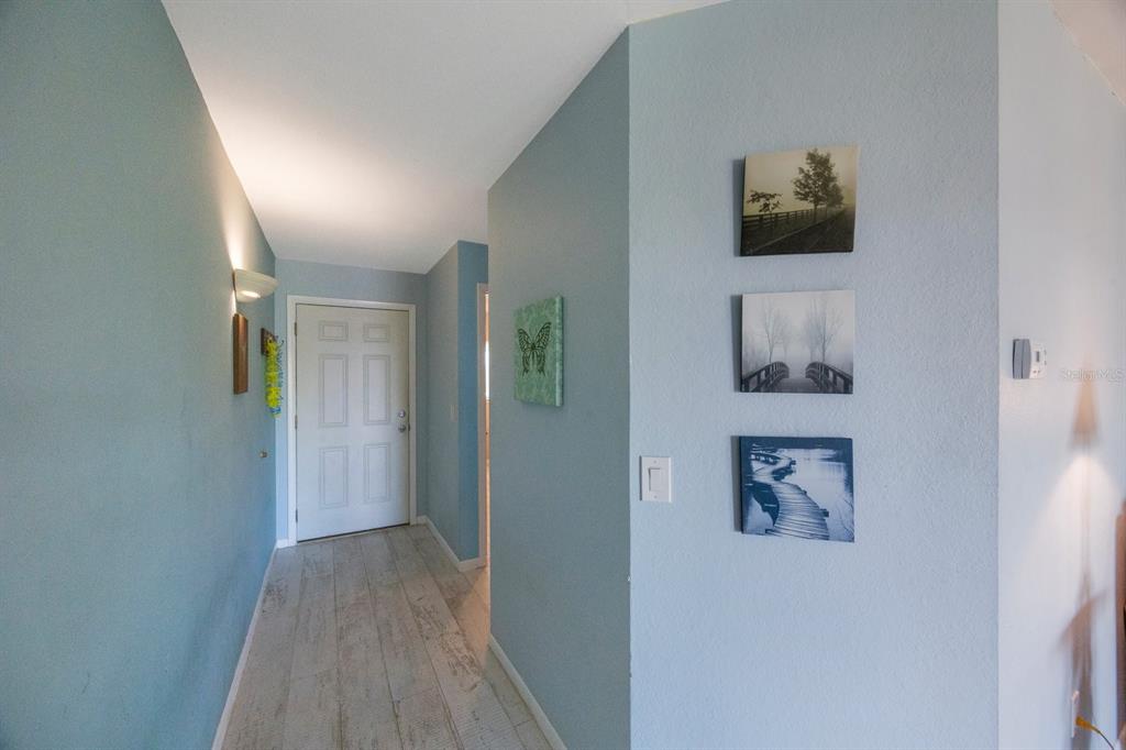 An entryway features light blue walls, wood-look tile flooring, and a white front door — 1125 PINELLAS BAYWAY S UNIT 305, ST PETERSBURG, FL