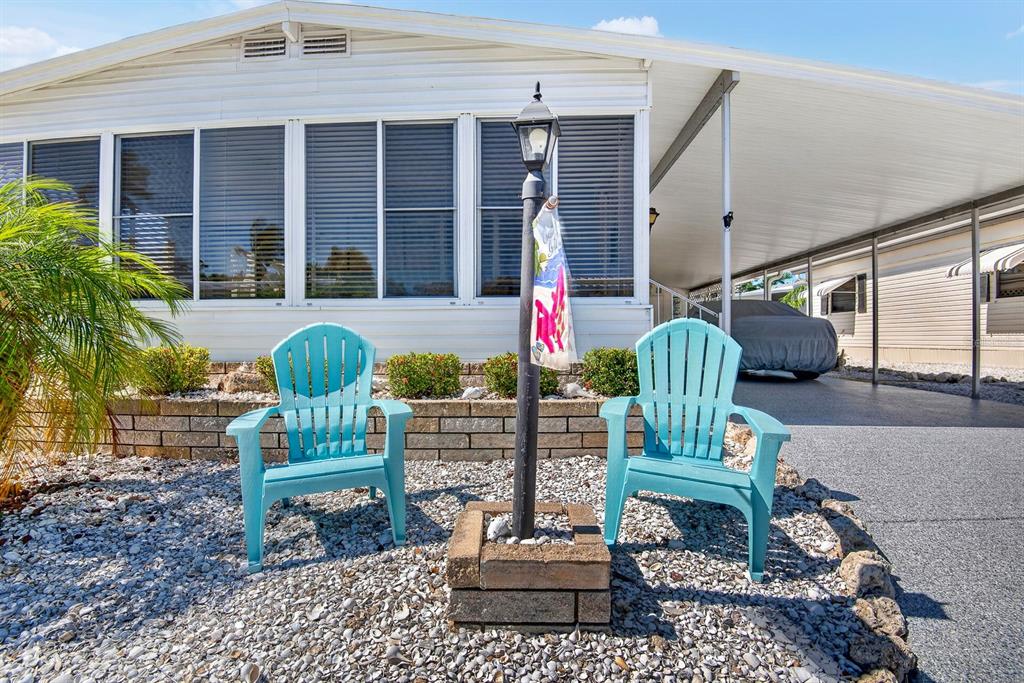 Two light blue Adirondack chairs sit on a gravel yard in front of a mobile home — 42 CABALLO WAY, BRADENTON, FL