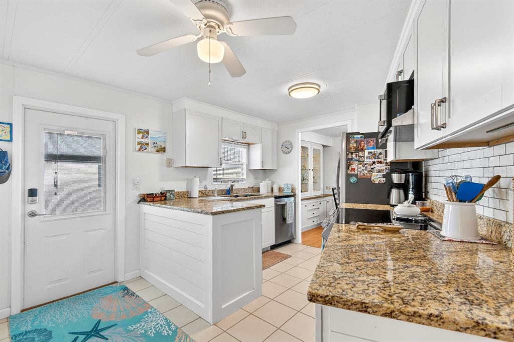 A kitchen features white cabinets, granite countertops, a ceiling fan, and a tile floor — 42 CABALLO WAY, BRADENTON, FL