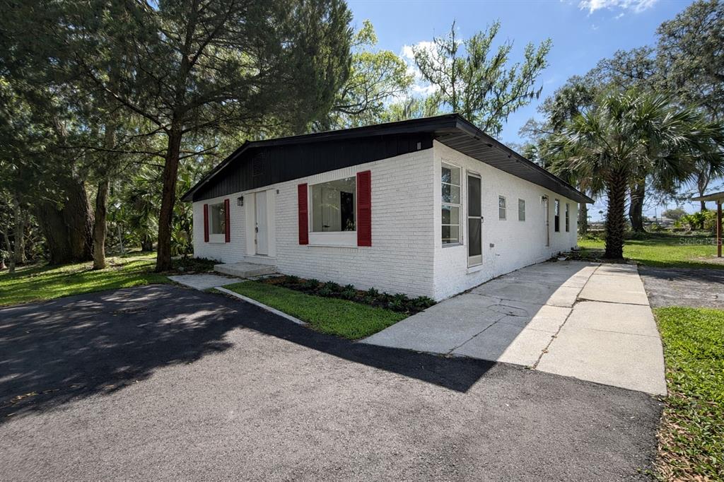 A white brick house with red shutters and a dark roof sits on a lot — 502 NW CRYSTAL STREET, CRYSTAL RIVER, FL