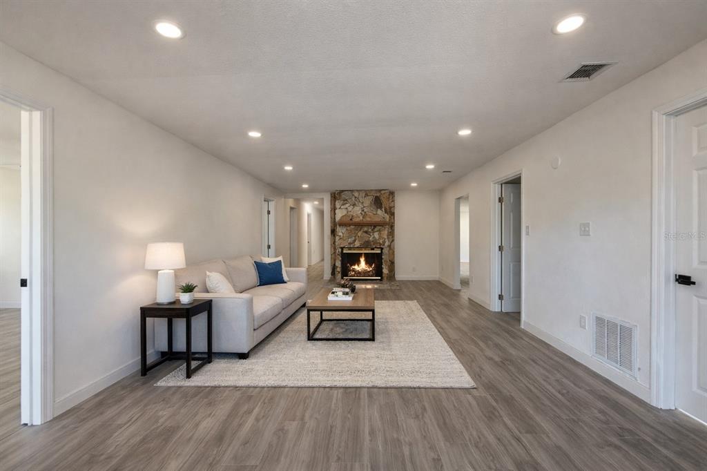 A living room features a stone fireplace, light gray flooring, and a neutral sofa — 502 NW CRYSTAL STREET, CRYSTAL RIVER, FL