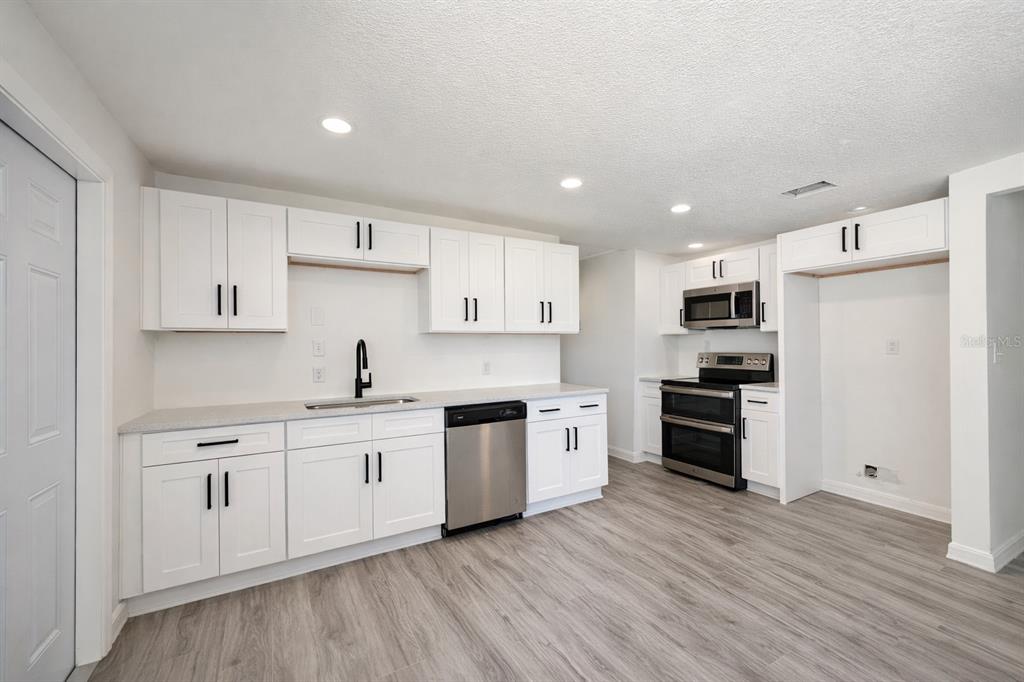 A kitchen with white cabinets, stainless steel appliances, and light wood-look flooring — 502 NW CRYSTAL STREET, CRYSTAL RIVER, FL