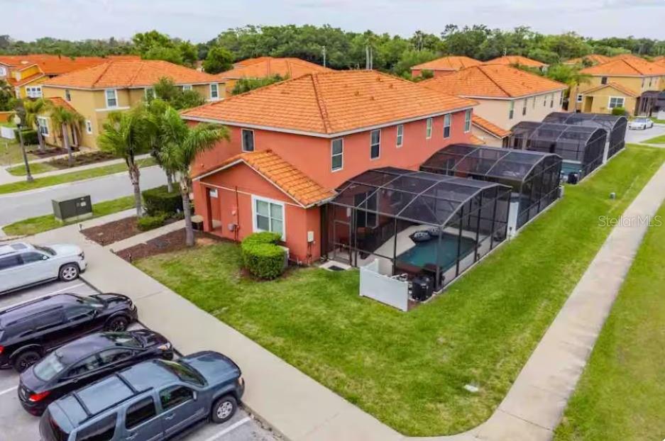 An aerial view of a two-story orange house with a screened-in pool and patio — 471 LAS FUENTES DRIVE, KISSIMMEE, FL