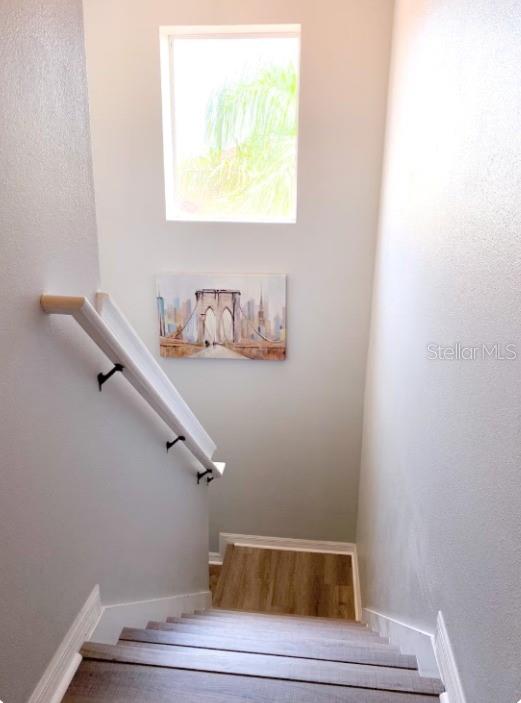 A staircase with wood-look steps and a white handrail leads down to a landing — 471 LAS FUENTES DRIVE, KISSIMMEE, FL