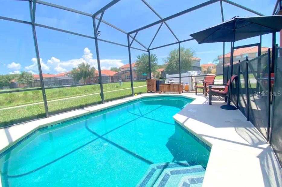 A screened-in swimming pool with a patio, outdoor furniture, and a view of neighboring houses — 471 LAS FUENTES DRIVE, KISSIMMEE, FL