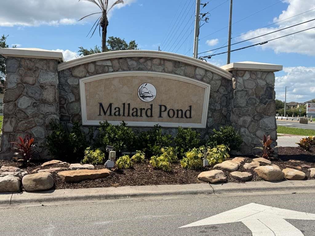 A stone monument sign for Mallard Pond stands in a landscaped garden bed — 3514 PINTAIL LANE, ST CLOUD, FL