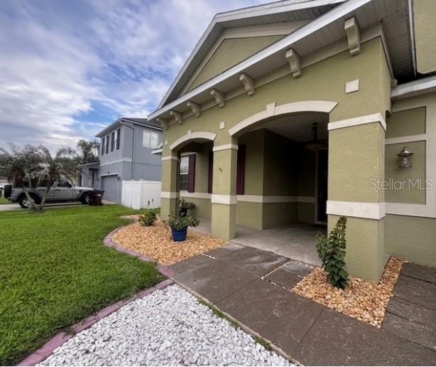The exterior of a green house features a covered front porch and a landscaped yard — 3514 PINTAIL LANE, ST CLOUD, FL