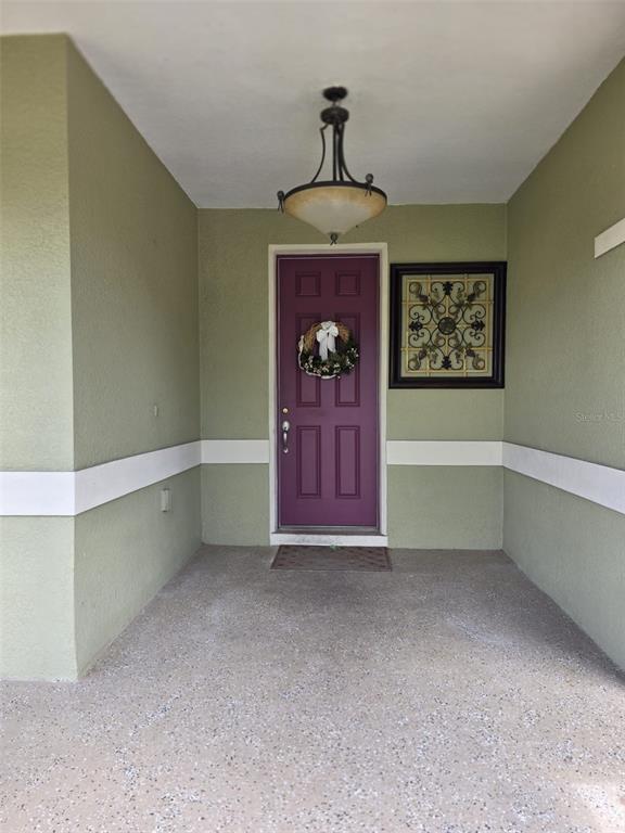 A covered entryway features a purple front door, a hanging light fixture, and wall art — 3514 PINTAIL LANE, ST CLOUD, FL