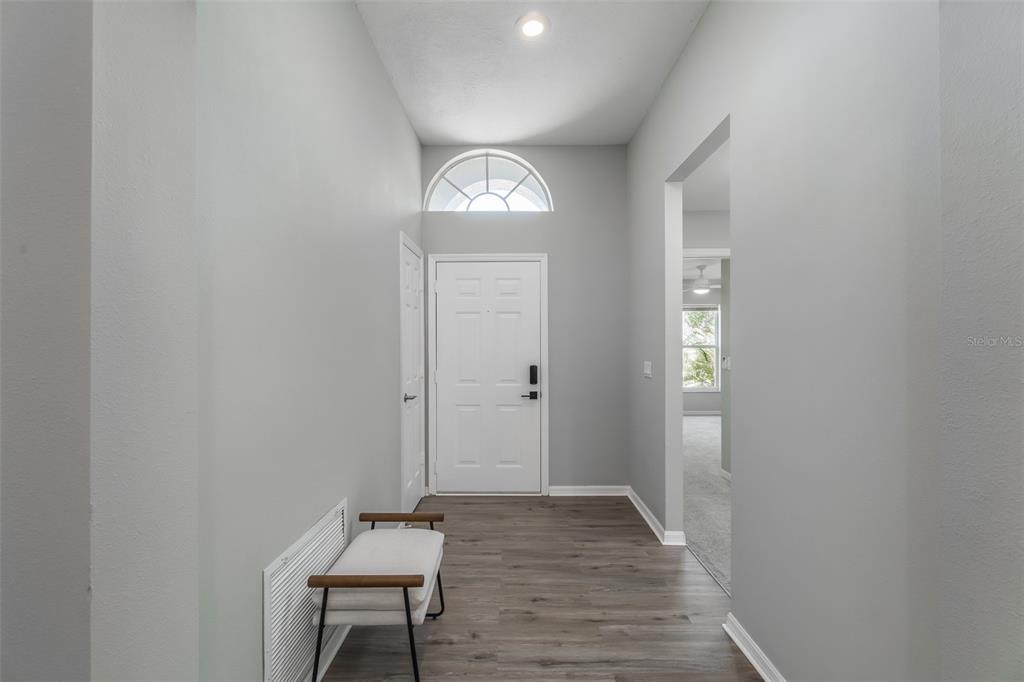 An entryway features light gray walls, wood-look flooring, a white front door, and a bench — 1707 BONDURANT WAY, BRANDON, FL