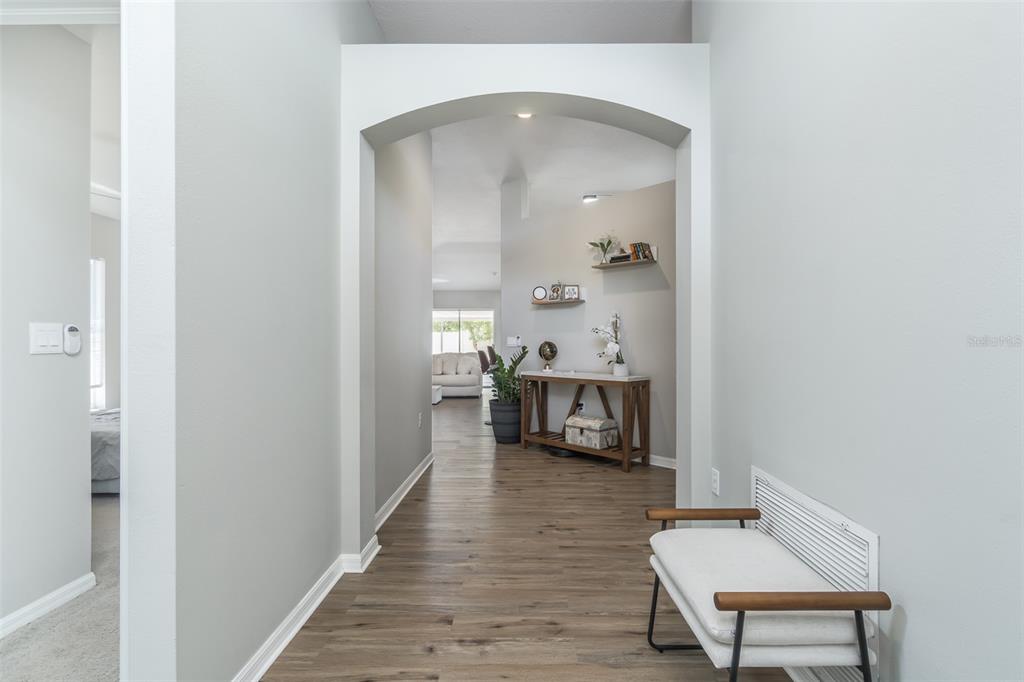 A hallway with wood-look flooring leads through an arched opening toward a living area — 1707 BONDURANT WAY, BRANDON, FL