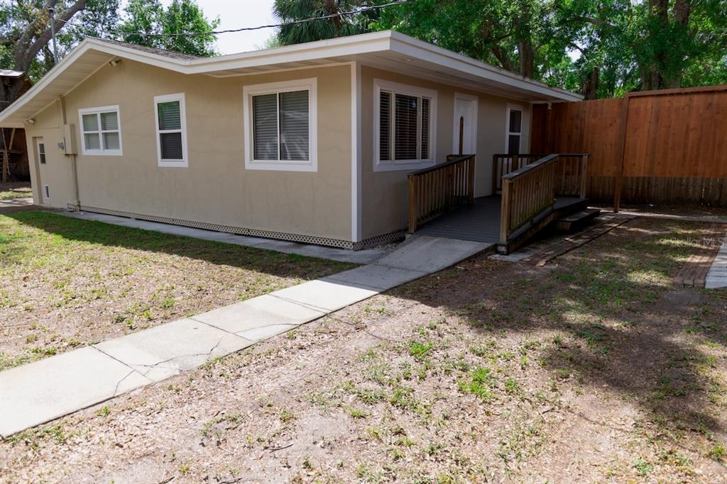 A tan house exterior with a wooden wheelchair ramp leading to the front entrance — 544 FARNUM DRIVE, TARPON SPRINGS, FL