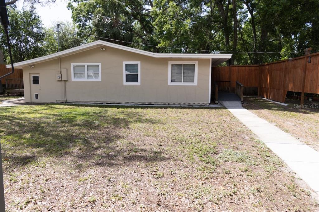 The exterior of a tan, single-story house features a sidewalk leading to a wooden ramp — 544 FARNUM DRIVE, TARPON SPRINGS, FL