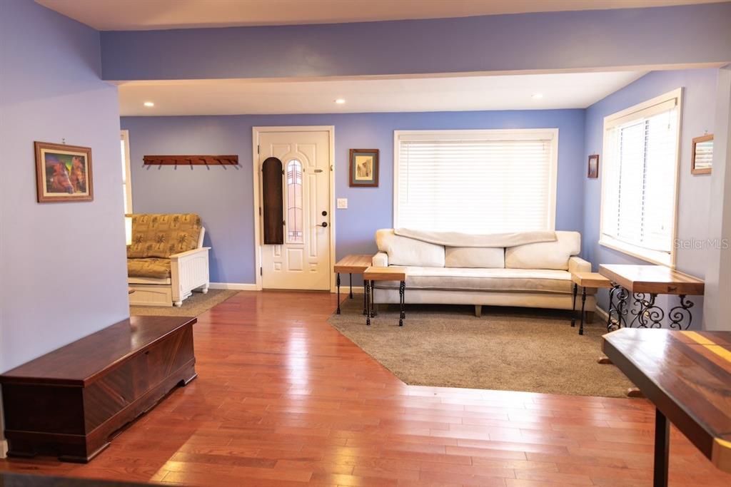 A living room features blue walls, hardwood floors, a white sofa, and a front door — 544 FARNUM DRIVE, TARPON SPRINGS, FL